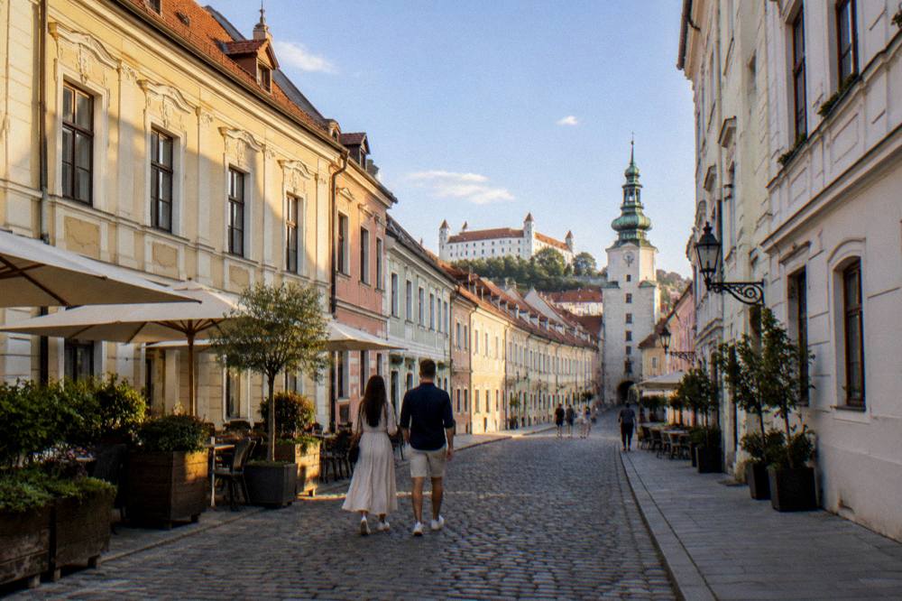 A couple walking down a narrow lane in the Bratislava Old Town in the evening