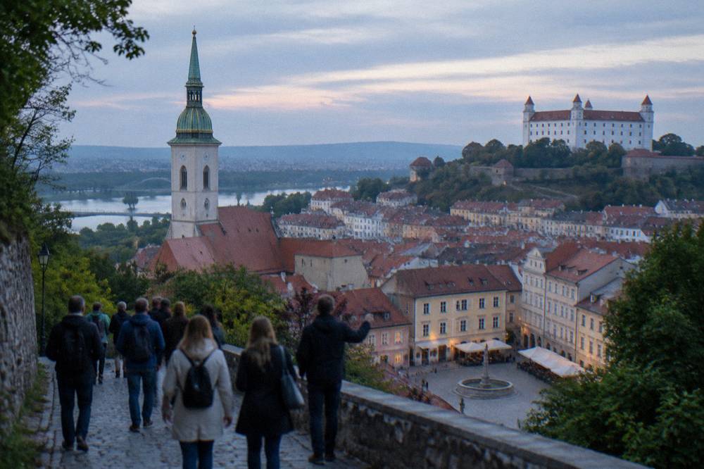 A group of tourists following a guide along the castle hill path above Bratislava's rooftops