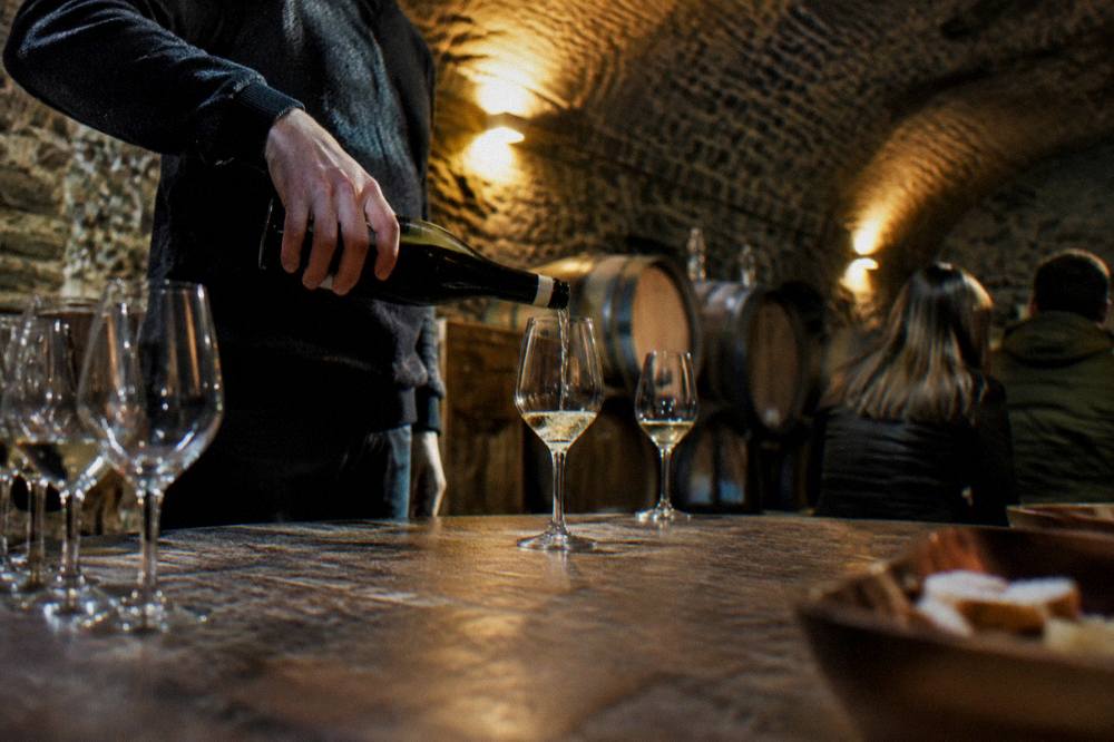 A local guide pouring wine for a small group in a vaulted cellar