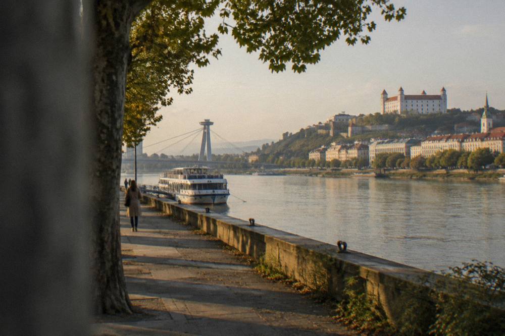 A Danube riverfront skyline at golden hour with a castle hill on one bank